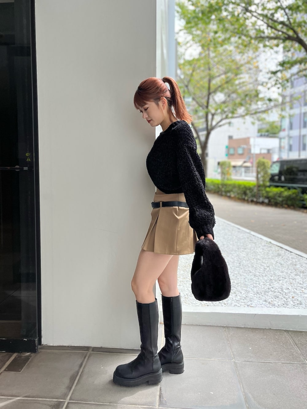ブラック系のハンドバッグ、ブラック系のニット/セーター、ベージュ系のスカートを着用したレディースの秋コーディネートの3枚目の写真