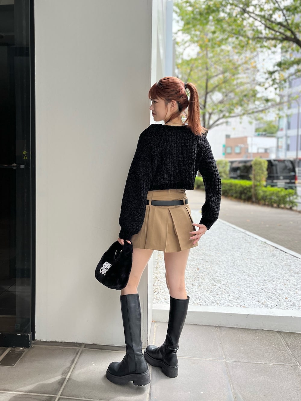 ブラック系のハンドバッグ、ブラック系のニット/セーター、ベージュ系のスカートを着用したレディースの秋コーディネートの4枚目の写真