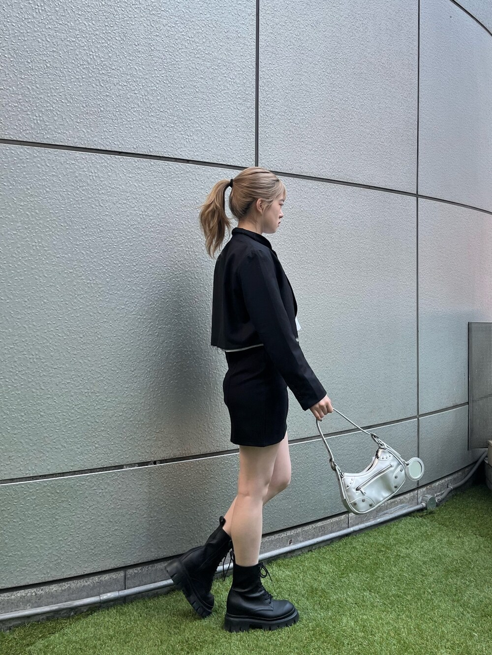 ブラック系のブーツ、シルバー系のハンドバッグ、ブラック系のテーラードジャケットを着用したレディースの春コーディネートの3枚目の写真