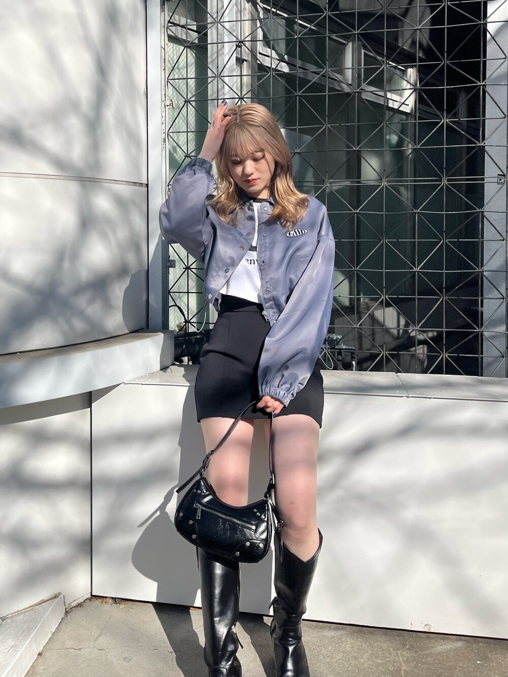 ブラック系のスカート、ブラック系のブーツ、ブラック系のハンドバッグを着用したレディースの冬コーディネートの6枚目の写真