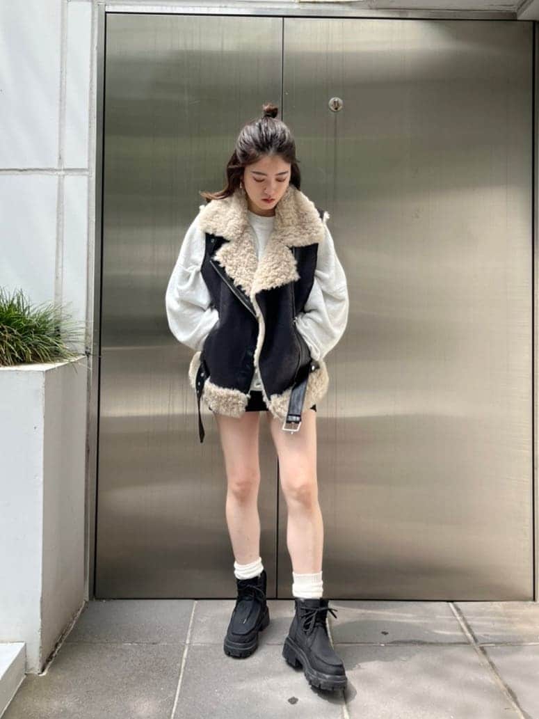 グレー系のスウェット、ブラック系のブーツ、ブラック系のスカートを着用したレディースの秋コーディネートの2枚目の写真