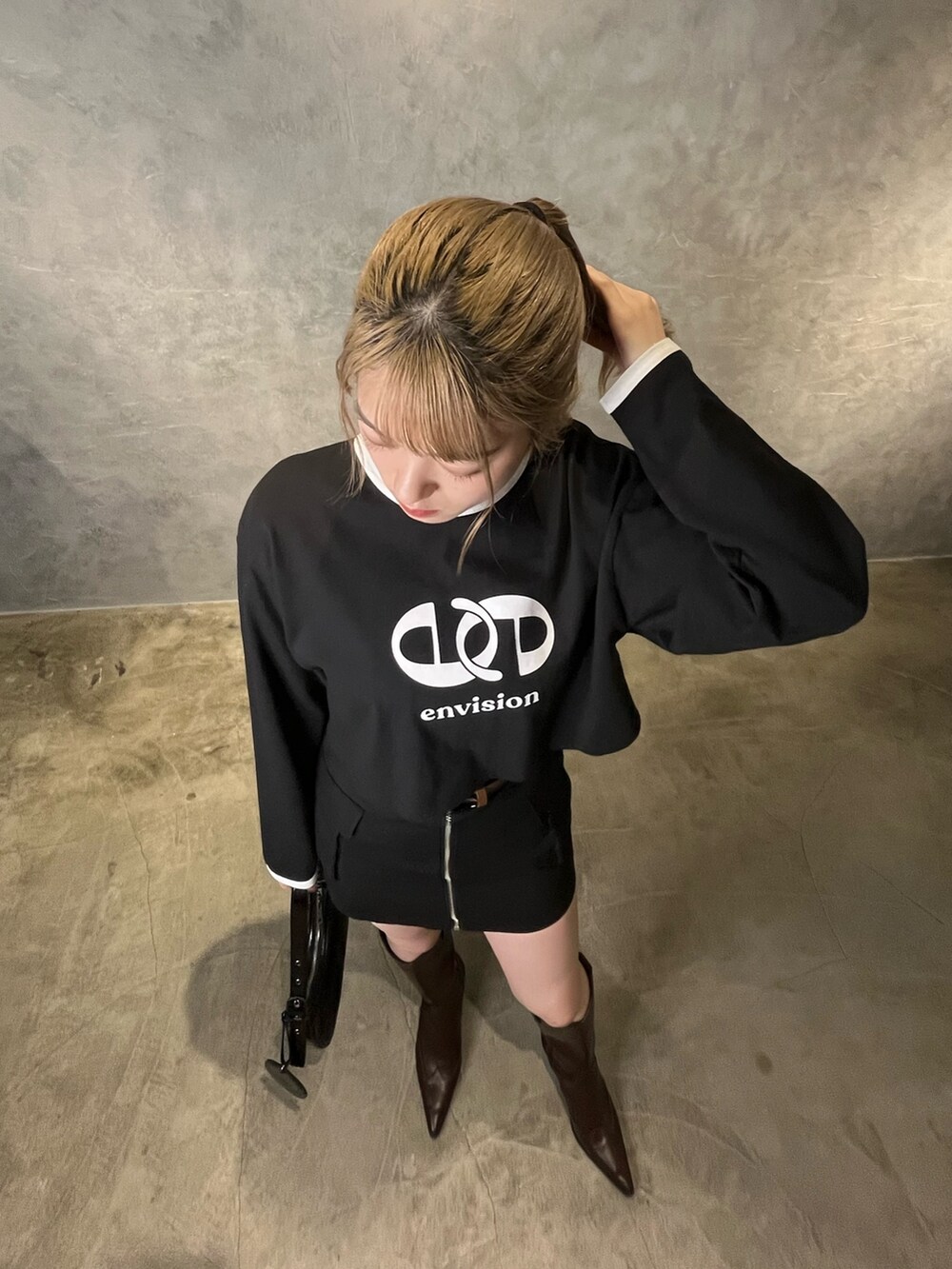 ブラック系のスカート、ブラウン系のブーツ、ブラック系のTシャツ/カットソーを着用したレディースの冬コーディネートの6枚目の写真