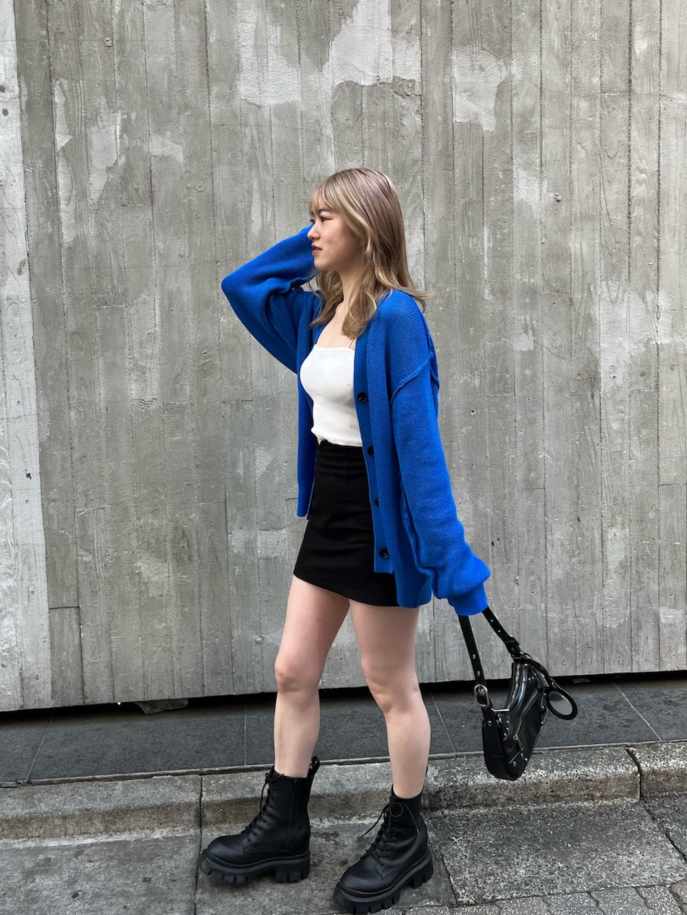 ブラック系のハンドバッグ、ブラック系のブーツ、ホワイト系のキャミソールを着用したレディースの春コーディネートの3枚目の写真