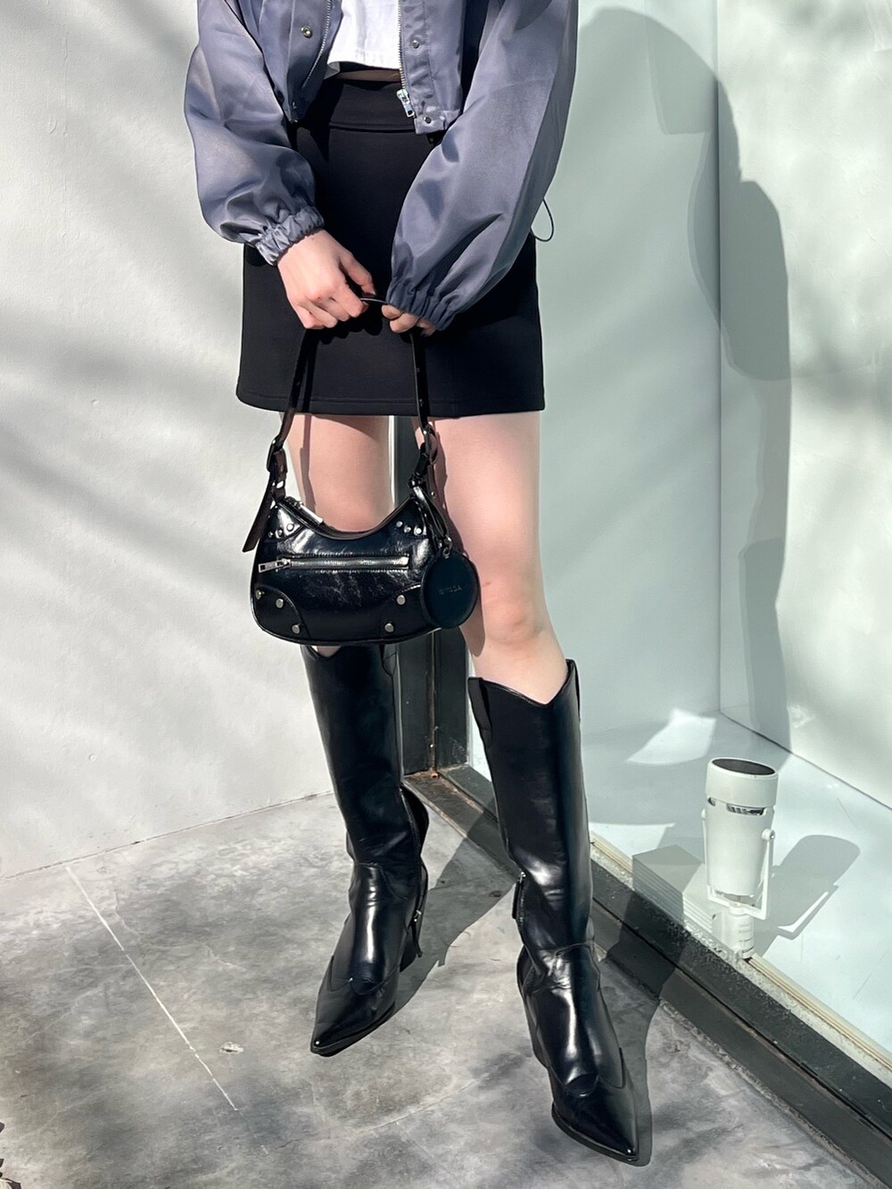 ブラック系のスカート、ブラック系のブーツ、ブラック系のハンドバッグを着用したレディースの冬コーディネートの5枚目の写真