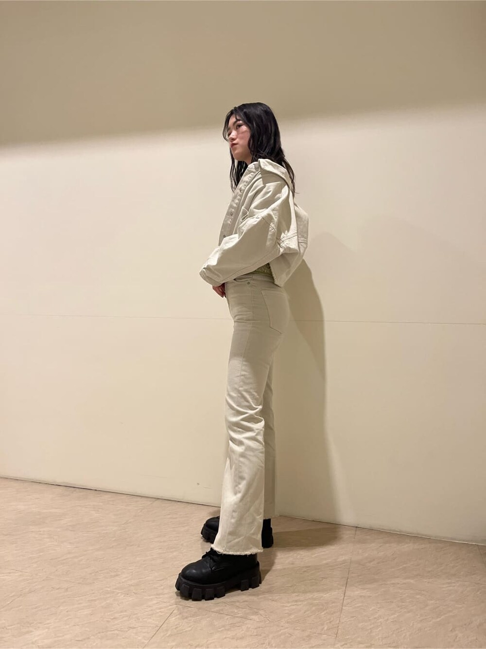 ブラック系のブーツ、ホワイト系のデニムジャケット、その他のポロシャツを着用したレディースの春コーディネートの3枚目の写真