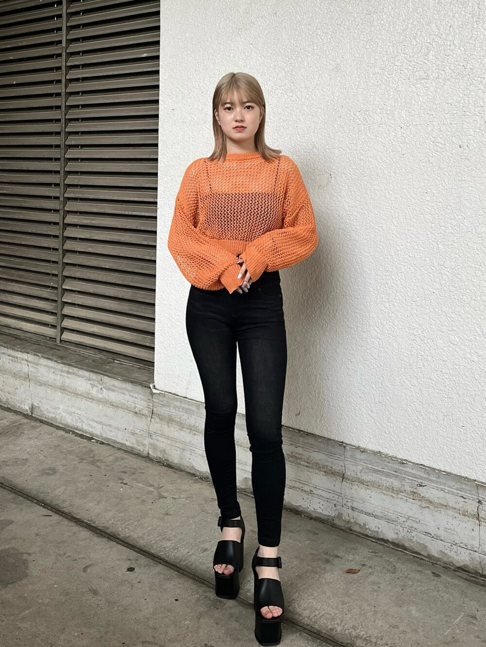 ブラック系のキャミソール、オレンジ系のニット/セーター、ブラック系のサンダルを着用したレディースの春コーディネートの2枚目の写真