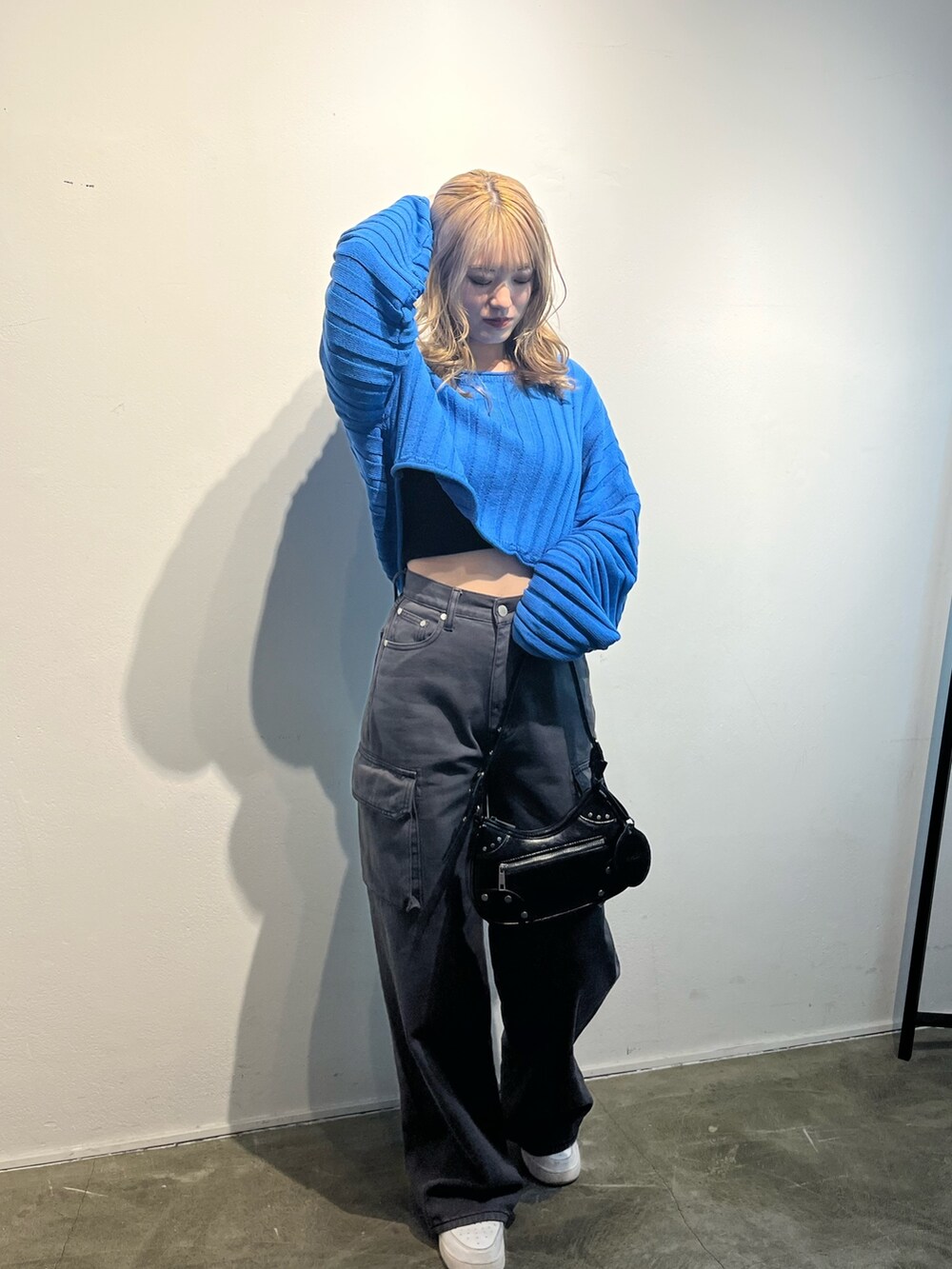 ブラック系のハンドバッグ、ブラック系のデニムパンツ、ブルー系のニット/セーターを着用したレディースの冬コーディネートの2枚目の写真