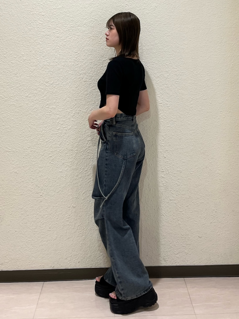 ブルー系のデニムパンツ、ブラック系のTシャツ/カットソー、ブラック系のサンダルを着用したレディースの夏コーディネートの3枚目の写真