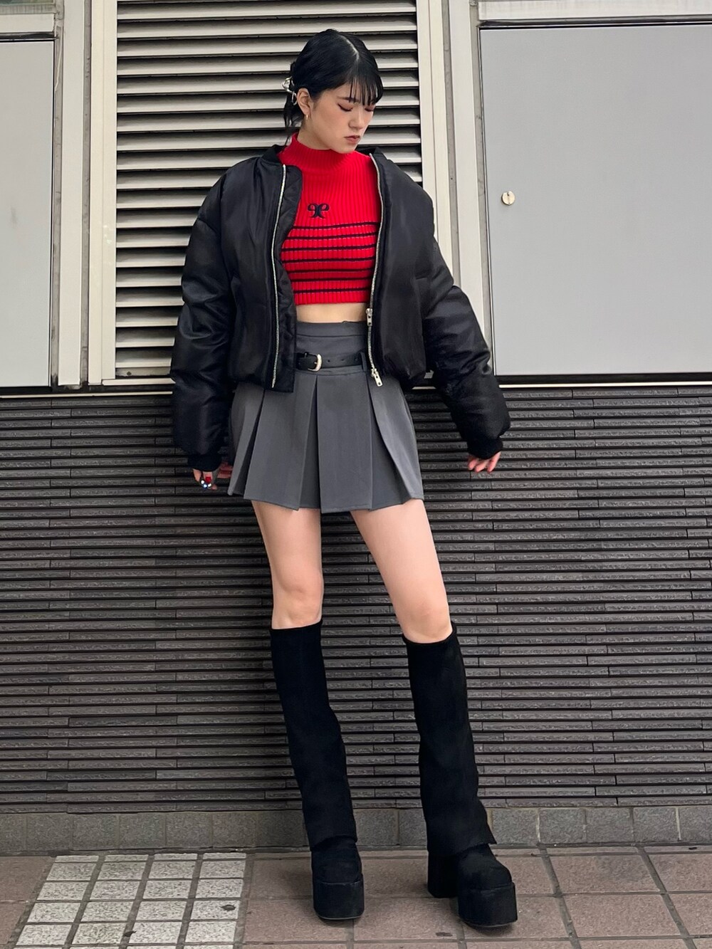 グレー系のスカート、レッド系のニット/セーター、ブラック系のブーツを着用したレディースの秋コーディネートの2枚目の写真