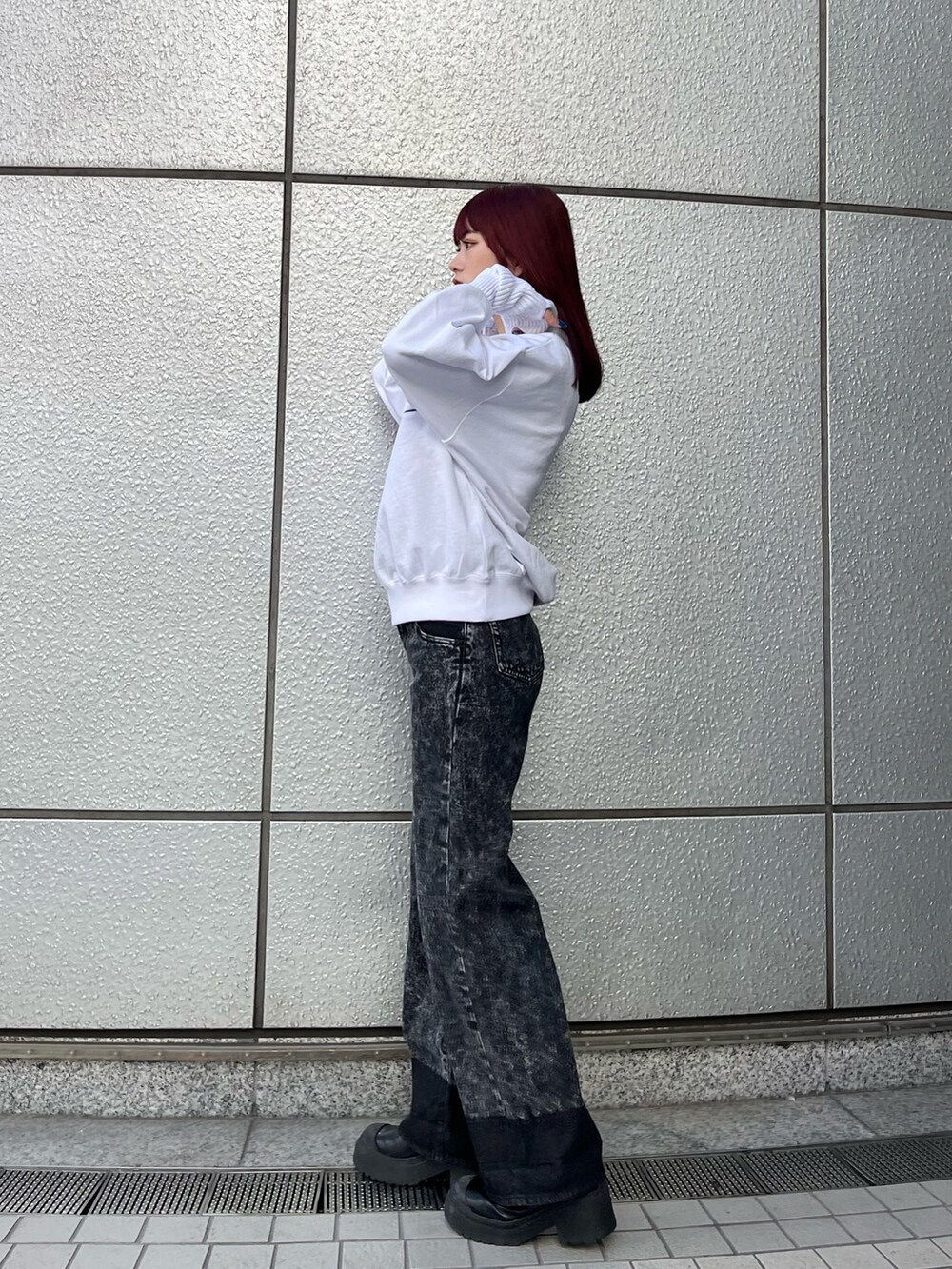 ホワイト系のスウェット、ブラック系のデニムパンツ、ブラック系のブーツを着用したレディースの秋コーディネートの3枚目の写真