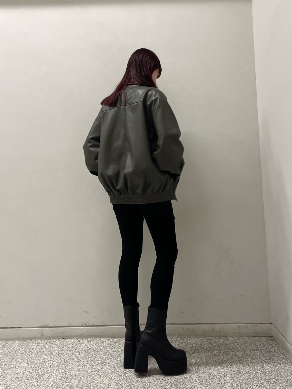 グレー系のブルゾン、ブラック系のデニムパンツ、ブラック系のニット/セーターを着用したレディースの冬コーディネートの3枚目の写真