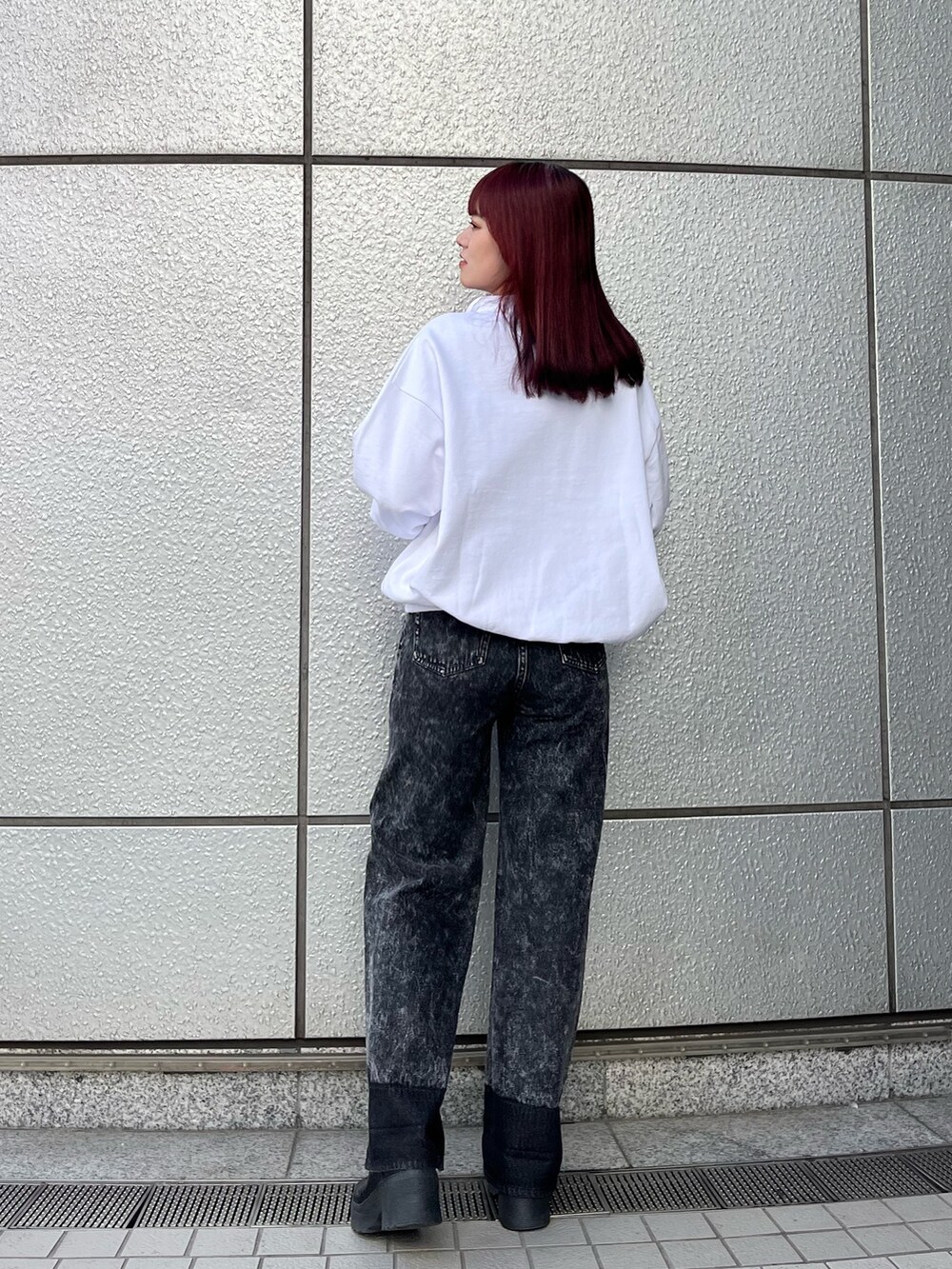 ホワイト系のスウェット、ブラック系のデニムパンツ、ブラック系のブーツを着用したレディースの秋コーディネートの4枚目の写真