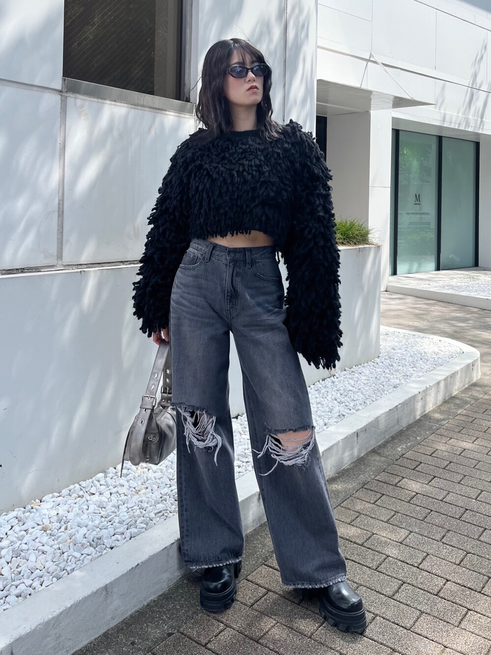 ブラック系のブーツ、グレー系のデニムパンツ、ブラック系のニット/セーターを着用したレディースの秋コーディネートの2枚目の写真