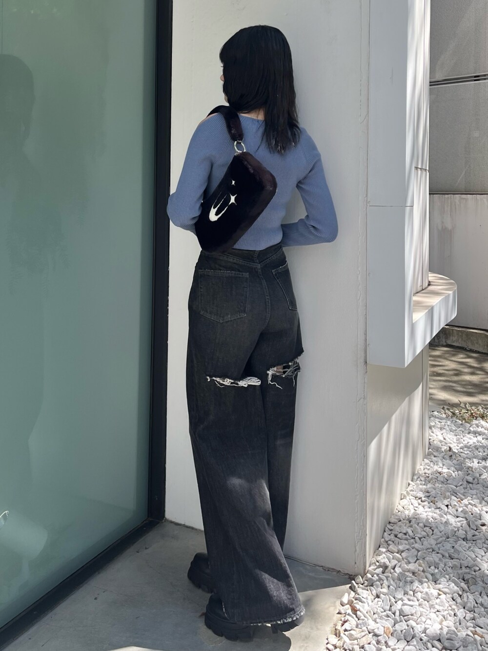 ブラック系のデニムパンツ、ブラック系のブーツ、ブルー系のニット/セーターを着用したレディースの秋コーディネートの2枚目の写真