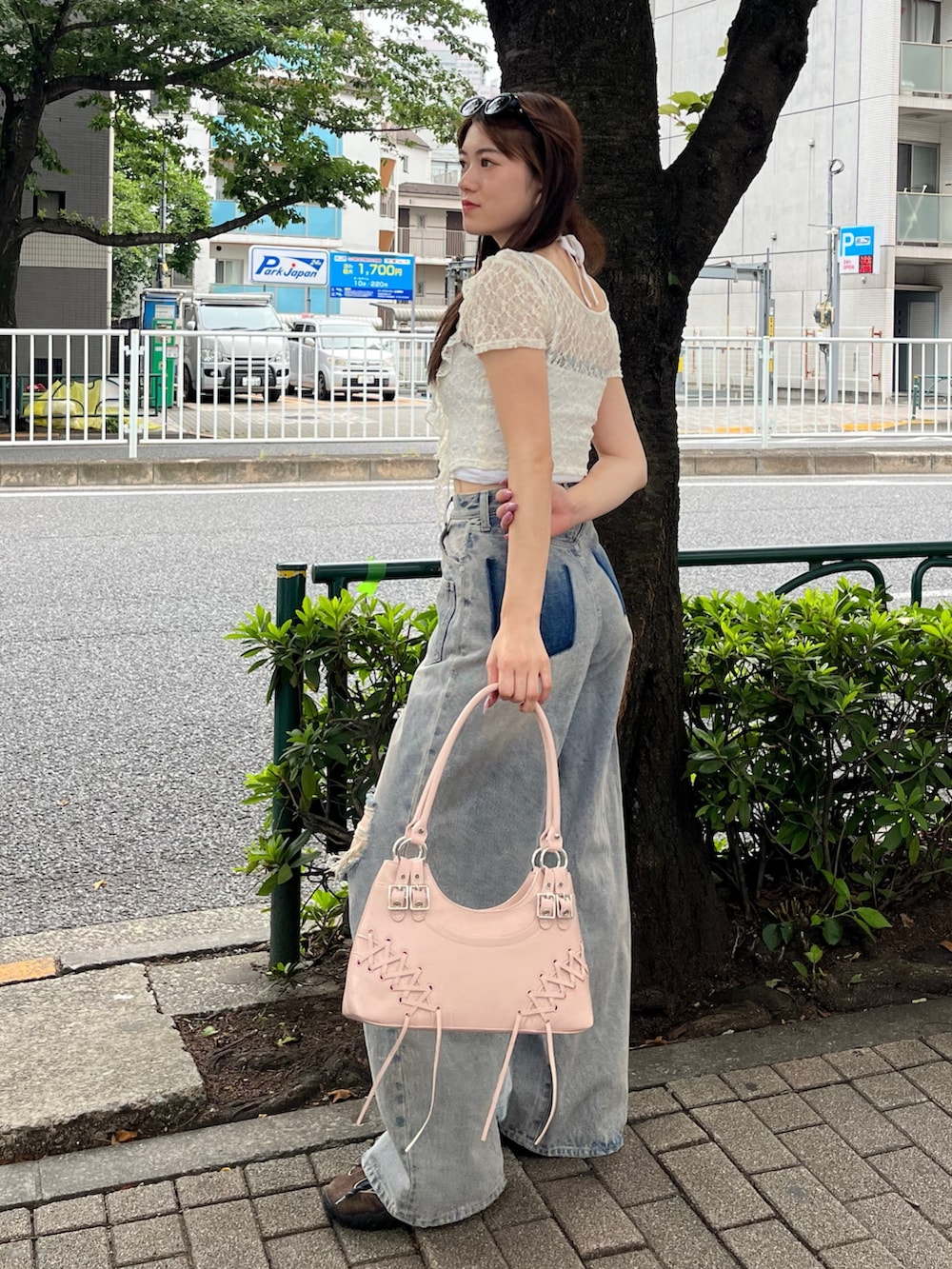 ブルー系のデニムパンツ、ブラウン系のスニーカー、ピンク系のショルダーバッグを着用したレディースの夏コーディネートの2枚目の写真