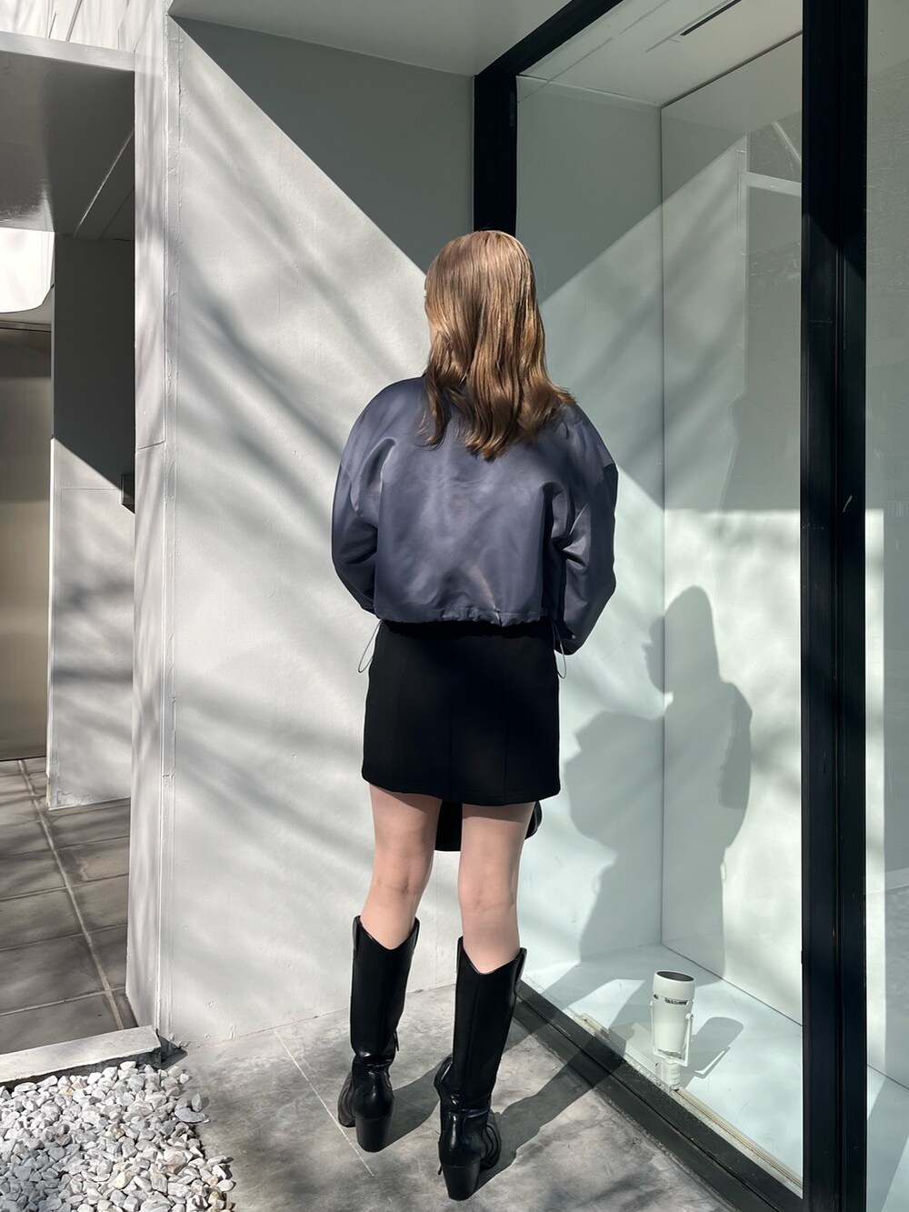 ブラック系のスカート、ブラック系のブーツ、ブラック系のハンドバッグを着用したレディースの冬コーディネートの3枚目の写真