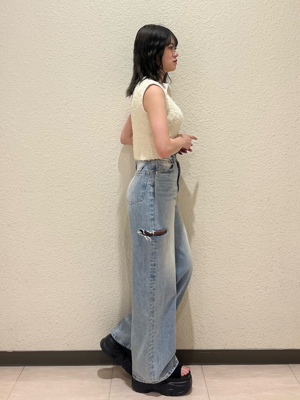 ブルー系のデニムパンツ、ブラック系のサンダル、ホワイト系のタンクトップを着用したレディースの夏コーディネートの3枚目の写真