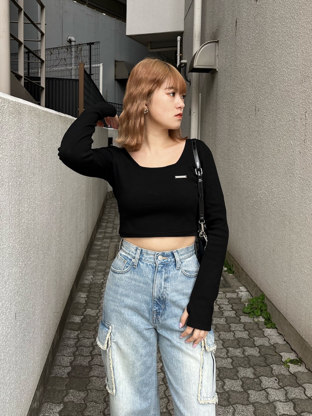 ブラック系のTシャツ/カットソー、ブラック系のスニーカー、ブルー系のデニムパンツを着用したレディースの春コーディネートの6枚目の写真