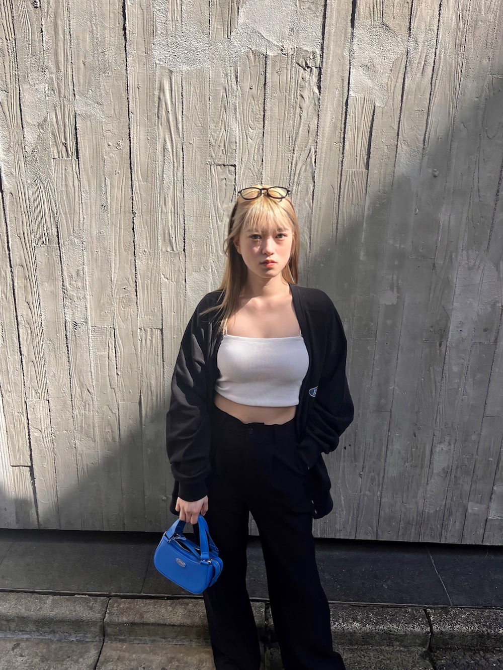 ホワイト系のキャミソール、ブラック系のカーディガン/ボレロ、ブルー系のハンドバッグを着用したレディースの春コーディネートの5枚目の写真