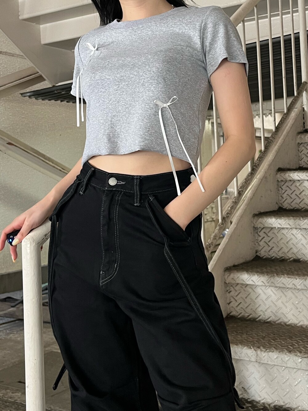 ブラック系のデニムパンツ、グレー系のTシャツ/カットソー、ブラック系のサンダルを着用したレディースの夏コーディネートの7枚目の写真