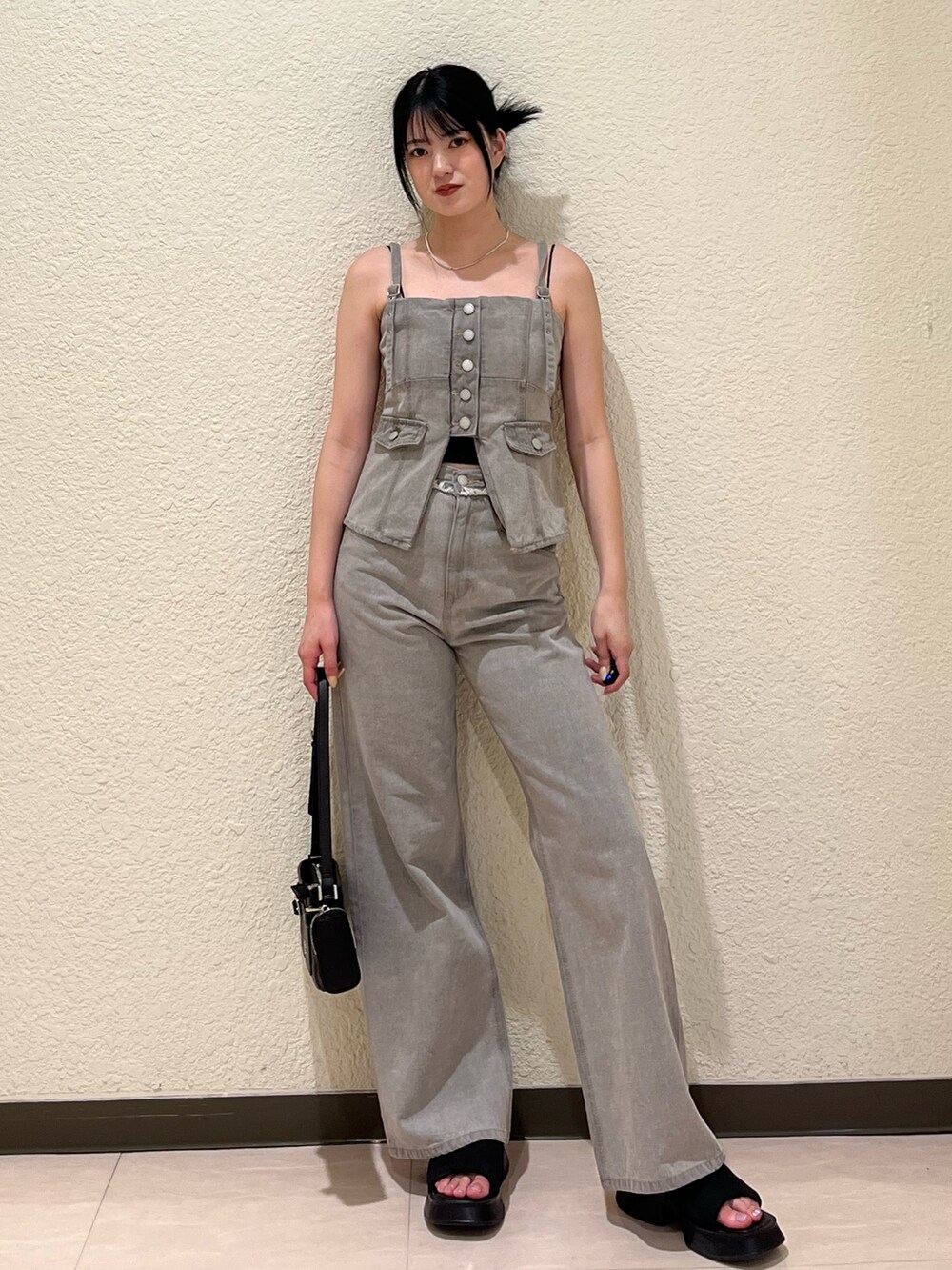 グレー系のデニムパンツ、グレー系のキャミソール、ブラック系のサンダルを着用したレディースの夏コーディネートの2枚目の写真
