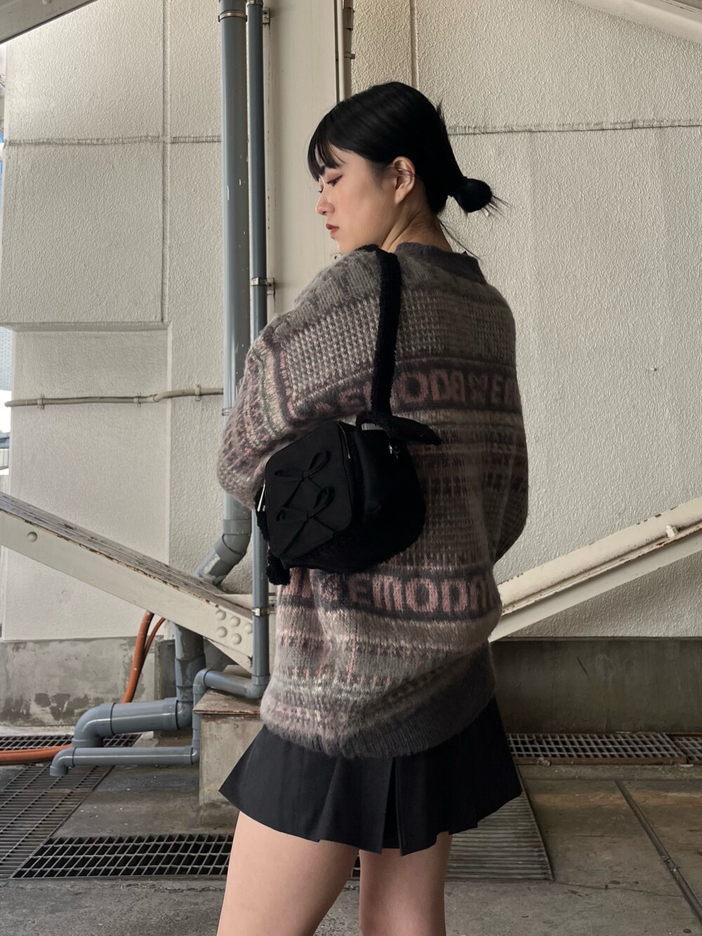 グレー系のスカート、ピンク系のニット/セーター、ブラック系のブーツを着用したレディースの冬コーディネートの7枚目の写真