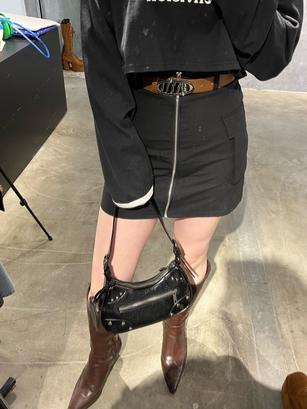 ブラック系のスカート、ブラウン系のブーツ、ブラック系のTシャツ/カットソーを着用したレディースの冬コーディネートの5枚目の写真