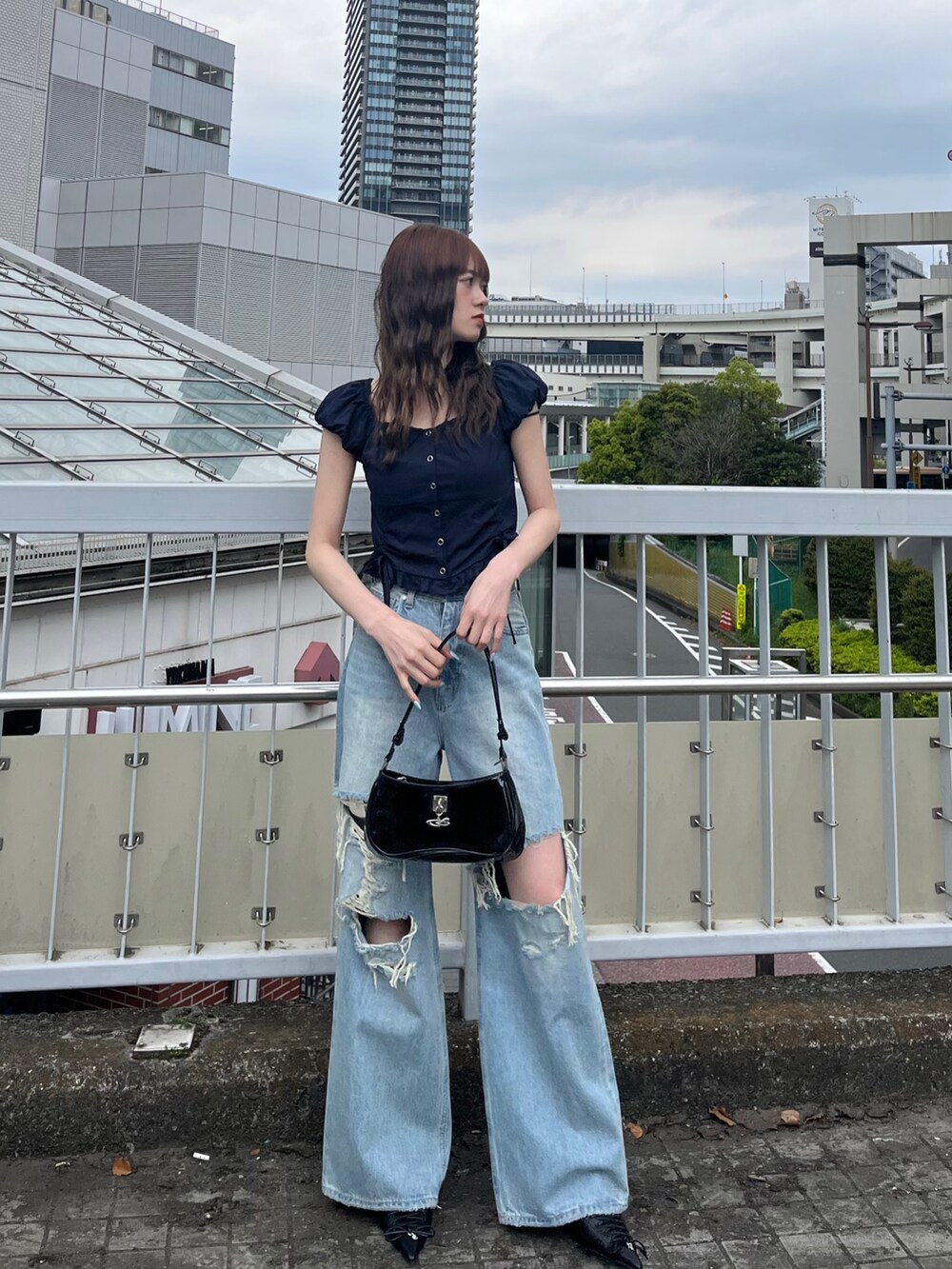 ブラック系のパンプス、ブラック系のショルダーバッグ、ブルー系のデニムパンツを着用したレディースの春コーディネートの2枚目の写真