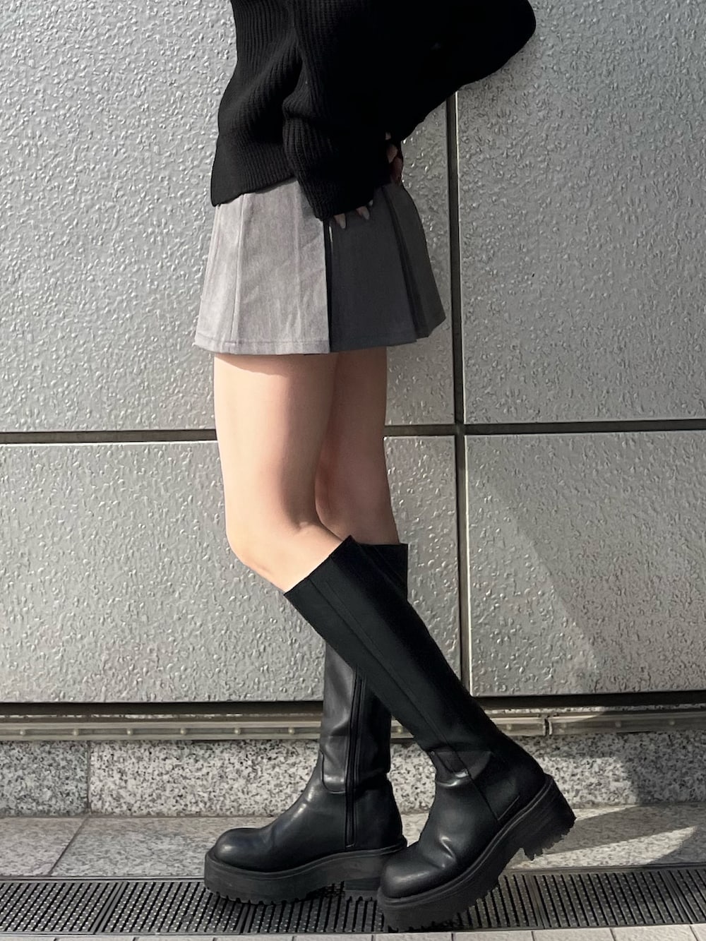 グレー系のスカート、ブラック系のブーツ、ブラック系のニット/セーターを着用したレディースの秋コーディネートの6枚目の写真