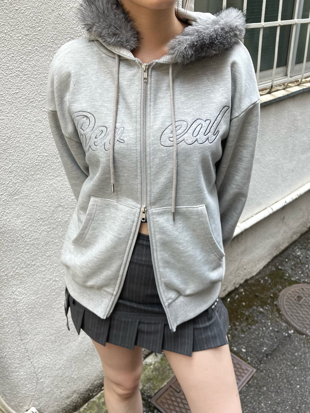 グレー系のパーカー、グレー系のスカート、ブラック系のブーツを着用したレディースの秋コーディネートの5枚目の写真