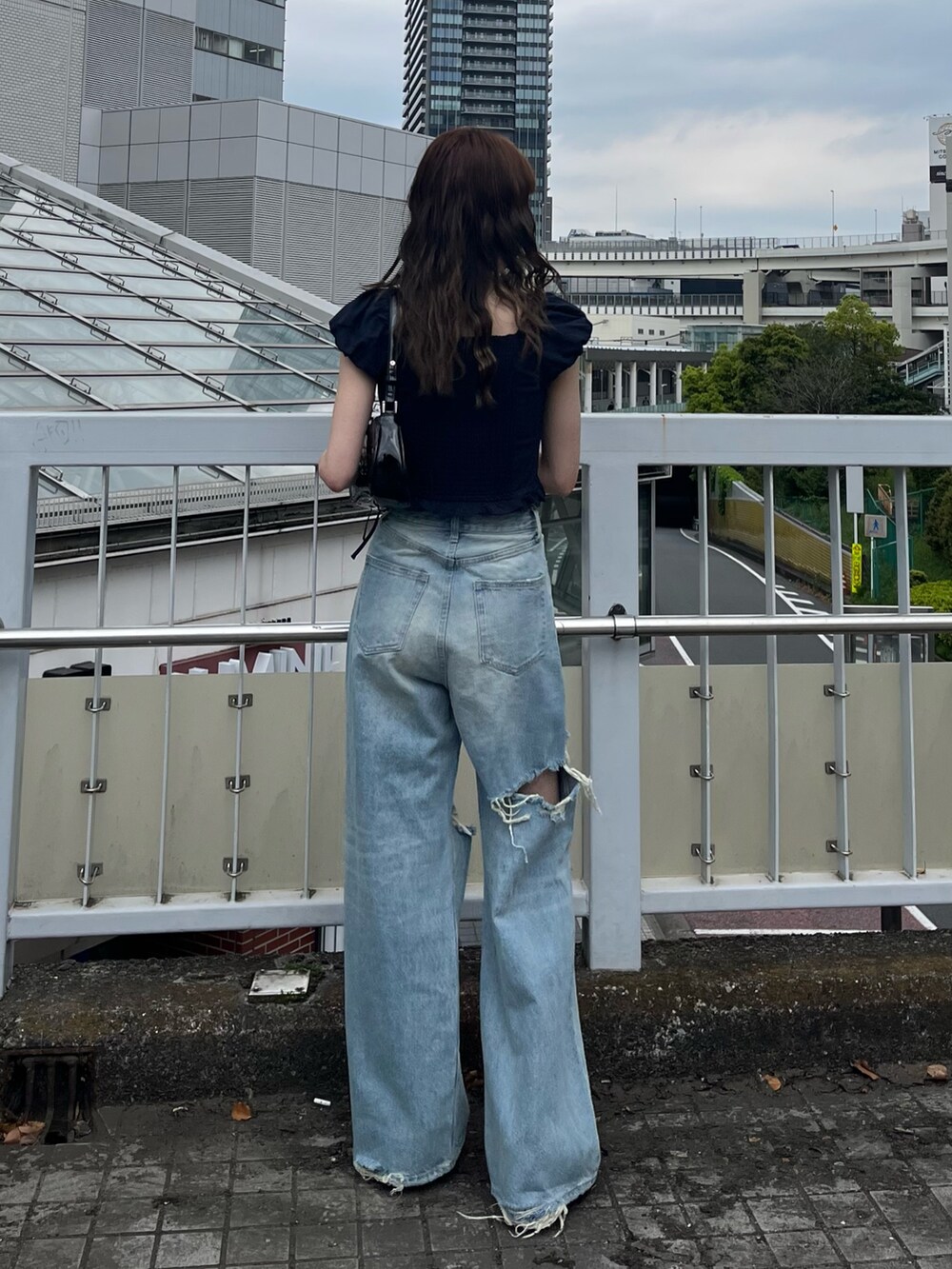 ブラック系のパンプス、ブラック系のショルダーバッグ、ブルー系のデニムパンツを着用したレディースの春コーディネートの3枚目の写真