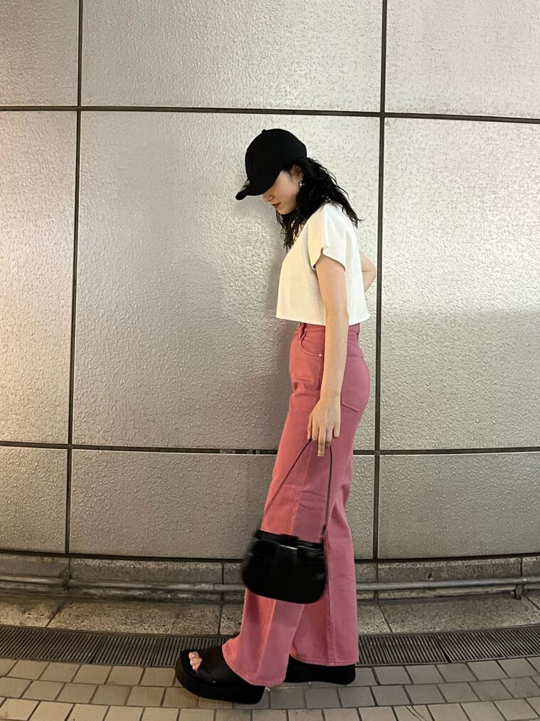 ピンク系のデニムパンツ、ブラック系のサンダル、ブラック系のハンドバッグを着用したレディースの夏コーディネートの3枚目の写真