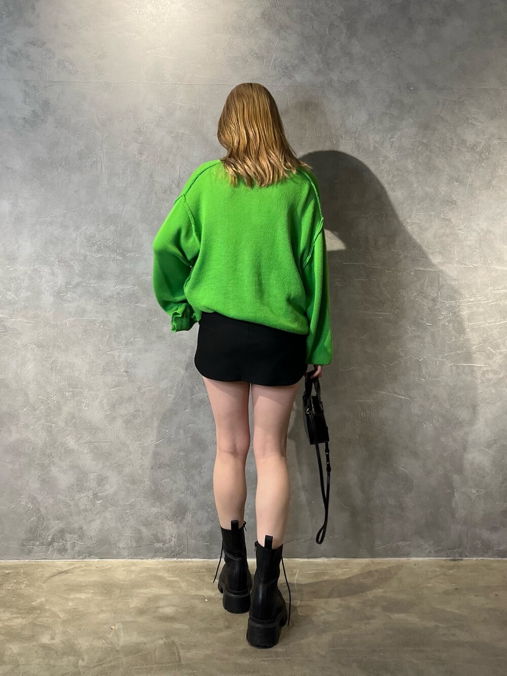 グリーン系のカーディガン/ボレロ、ブラック系のブーツ、ブラック系のスカートを着用したレディースの冬コーディネートの3枚目の写真