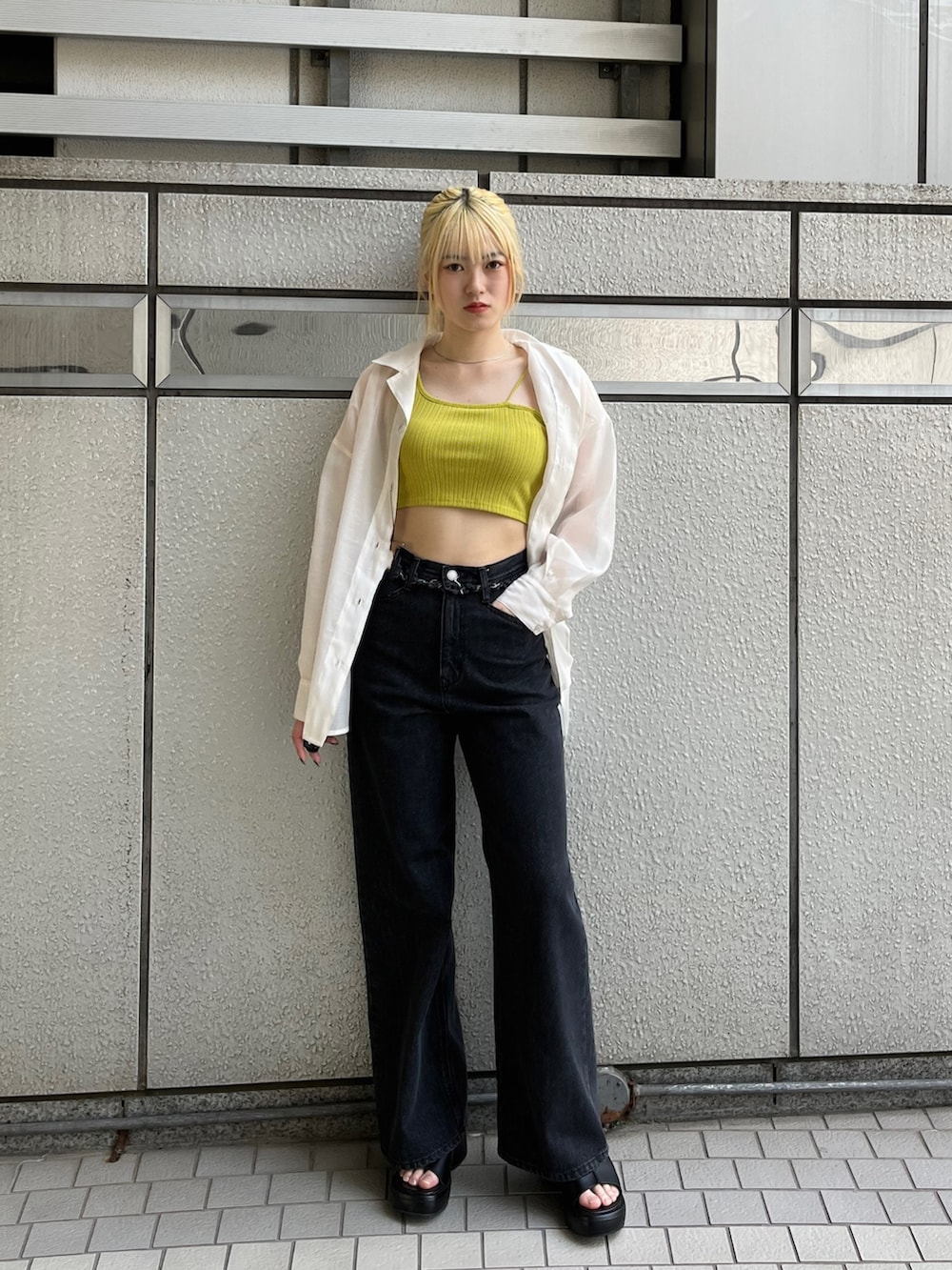 ブラック系のデニムパンツ、ブラック系のサンダル、イエロー系のタンクトップを着用したレディースの春コーディネートの2枚目の写真