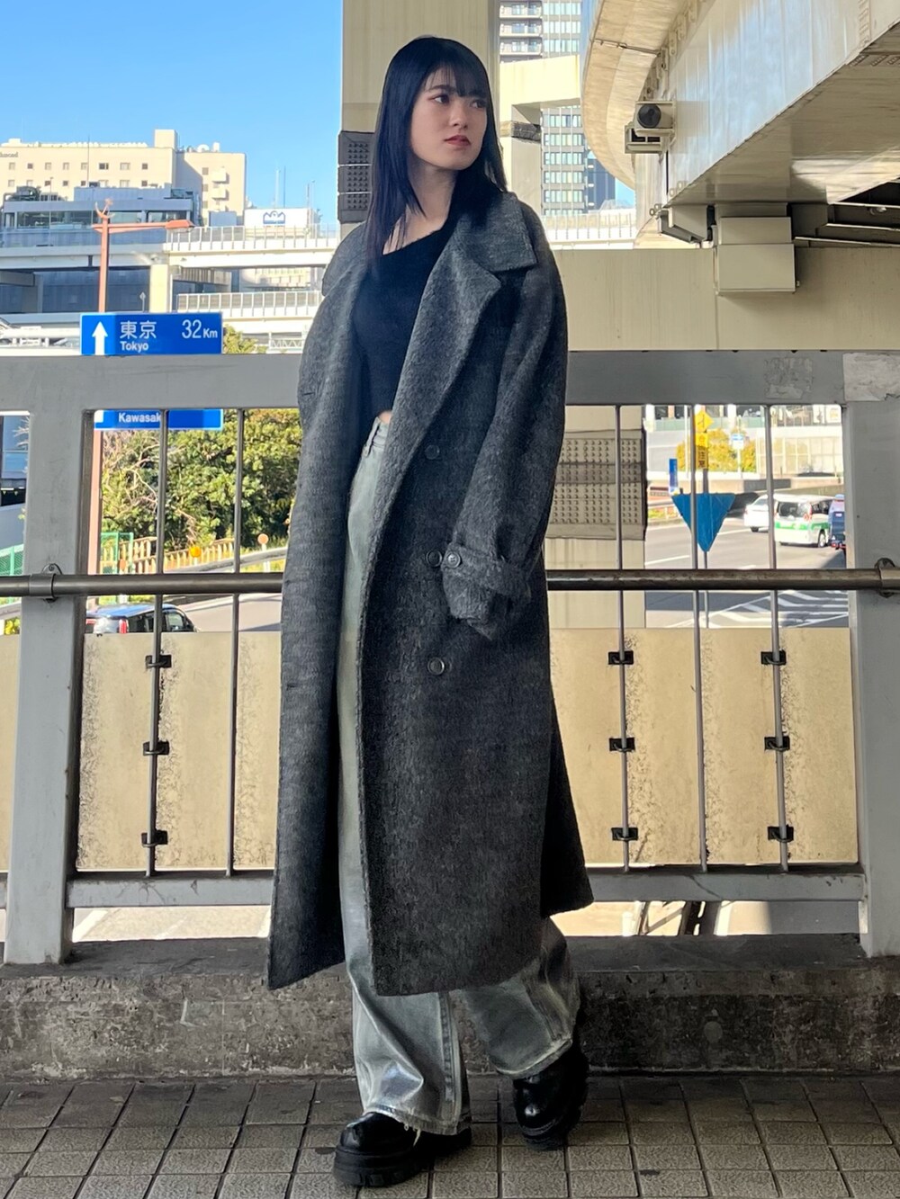 ブラック系のブーツ、ブラック系のニット/セーター、ブルー系のデニムパンツを着用したレディースの冬コーディネートの2枚目の写真