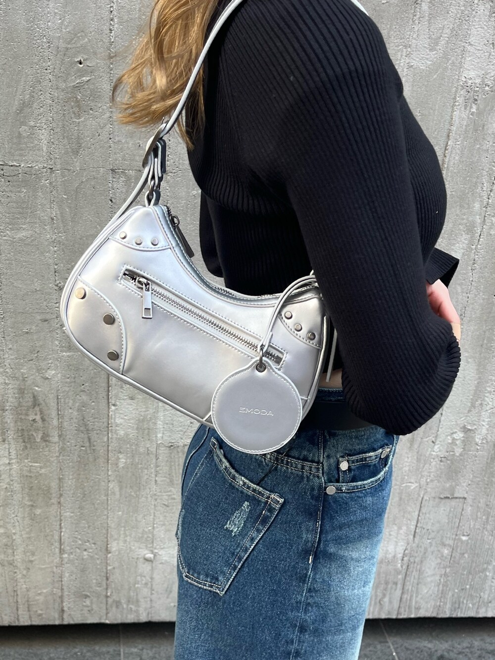 ブルー系のデニムパンツ、シルバー系のハンドバッグ、ブラック系のニット/セーターを着用したレディースの春コーディネートの8枚目の写真