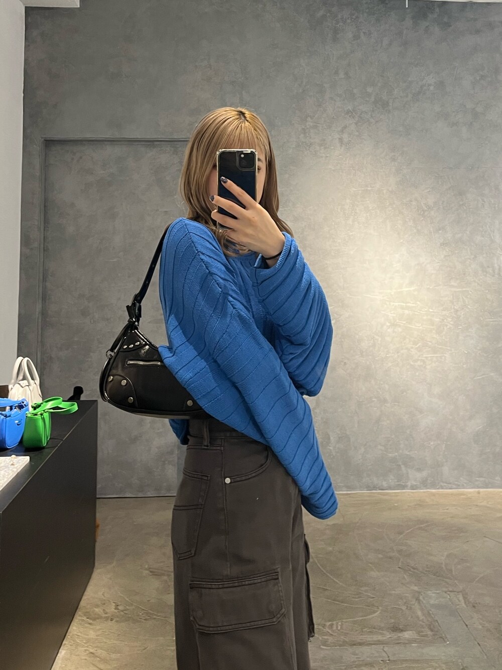 ブラック系のハンドバッグ、ブラック系のデニムパンツ、ブルー系のニット/セーターを着用したレディースの冬コーディネートの6枚目の写真