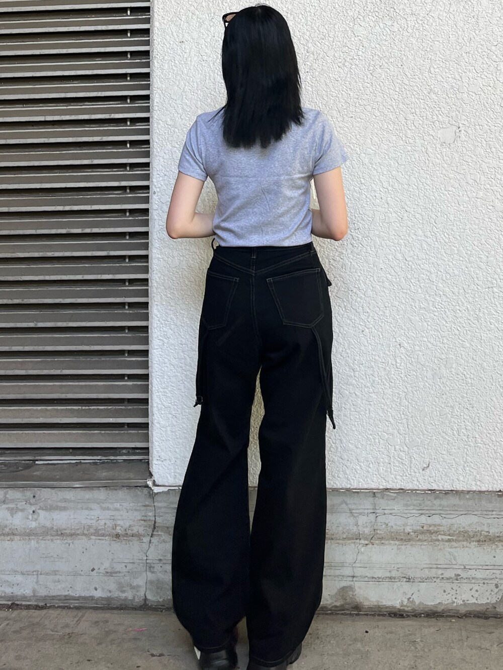 ブラック系のデニムパンツ、グレー系のTシャツ/カットソー、ブラック系のサンダルを着用したレディースの夏コーディネートの3枚目の写真