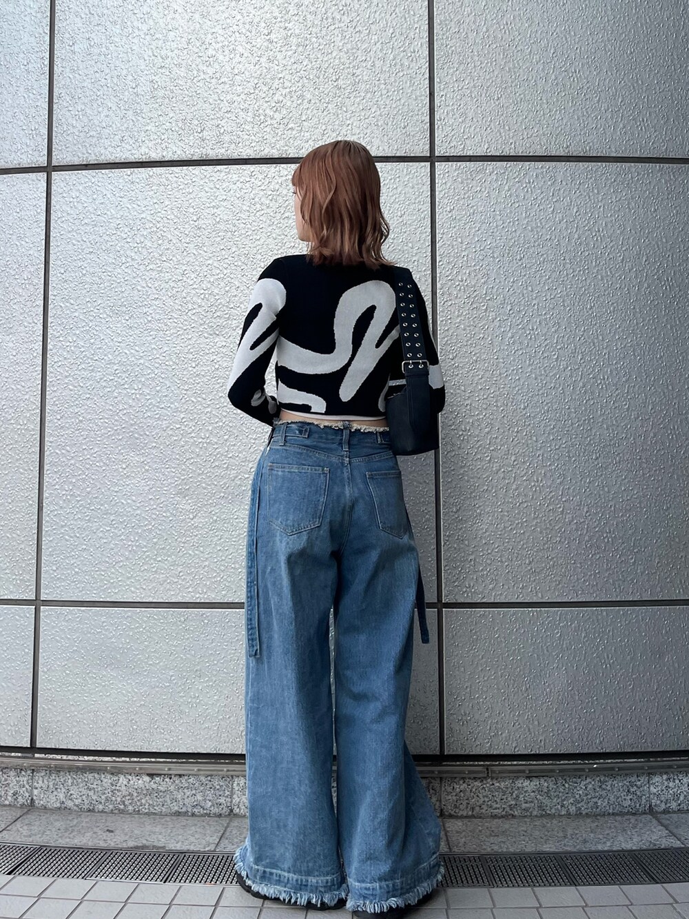 ブラック系のスニーカー、ブルー系のデニムパンツ、ホワイト系のキャミソールを着用したレディースの冬コーディネートの5枚目の写真