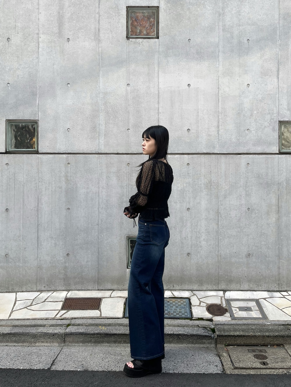 ブルー系のデニムパンツ、ブラック系のニット/セーター、ブラック系のサンダルを着用したレディースの春コーディネートの2枚目の写真