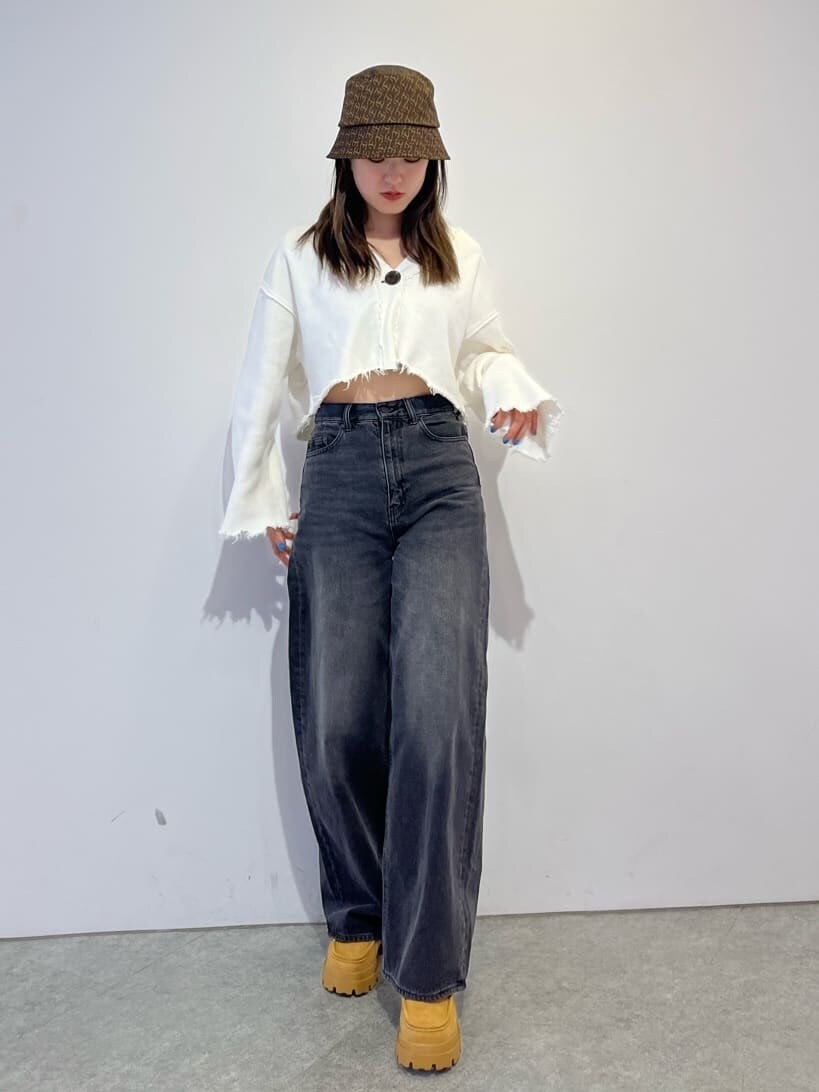 ブラウン系のブーツ、ホワイト系のカーディガン/ボレロ、グレー系のデニムパンツを着用したレディースの秋コーディネートの2枚目の写真