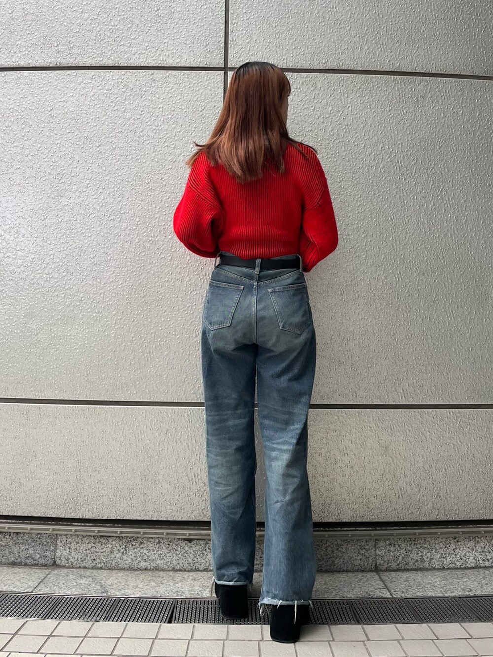 ブラック系のブーツ、ブルー系のデニムパンツ、レッド系のニット/セーターを着用したレディースの秋コーディネートの4枚目の写真