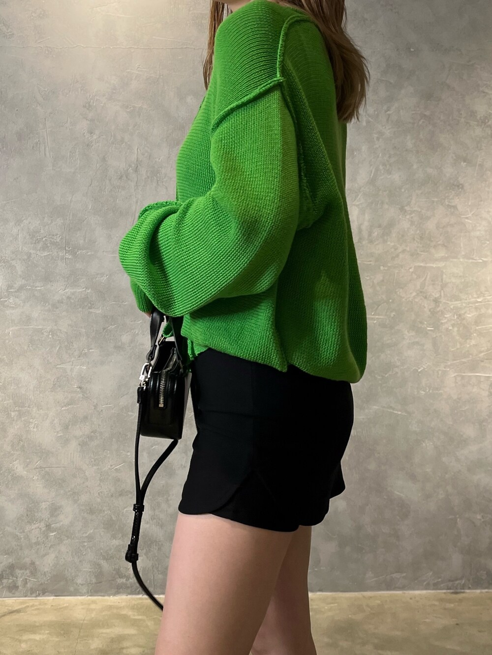 グリーン系のカーディガン/ボレロ、ブラック系のブーツ、ブラック系のスカートを着用したレディースの冬コーディネートの6枚目の写真