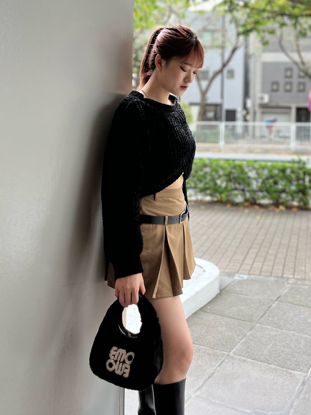 ブラック系のハンドバッグ、ブラック系のニット/セーター、ベージュ系のスカートを着用したレディースの秋コーディネートの6枚目の写真