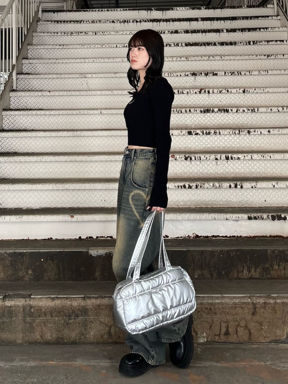 シルバー系のボストンバッグ、ブルー系のデニムパンツ、ブラック系のニット/セーターを着用したレディースの冬コーディネートの3枚目の写真