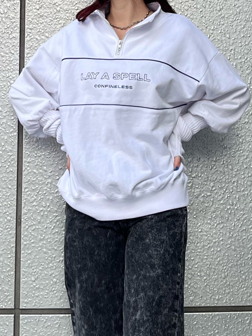 ホワイト系のスウェット、ブラック系のデニムパンツ、ブラック系のブーツを着用したレディースの秋コーディネートの5枚目の写真