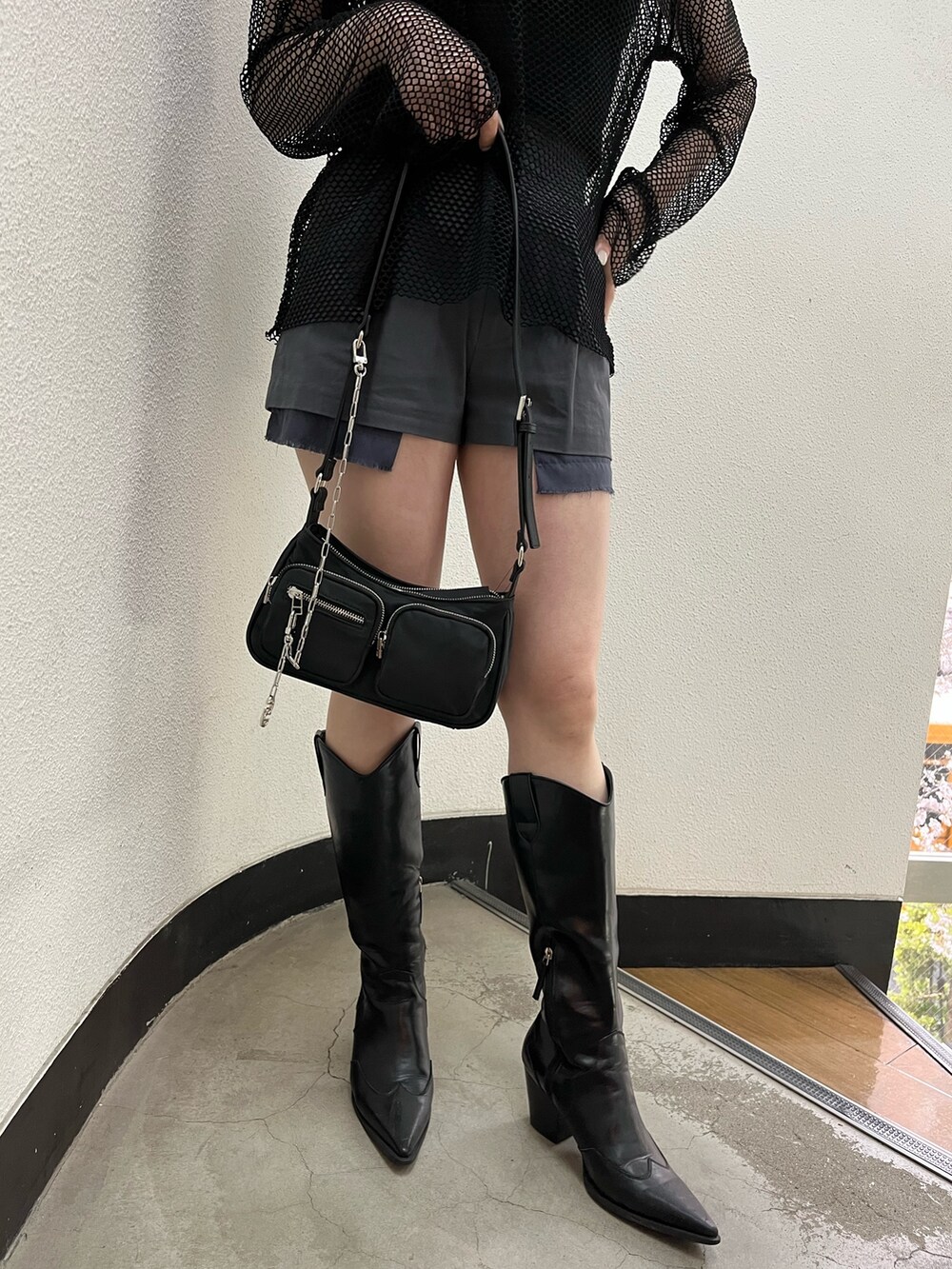 ブラック系のブーツ、ブラック系のキャミソール、ブラック系のハンドバッグを着用したレディースの夏コーディネートの6枚目の写真