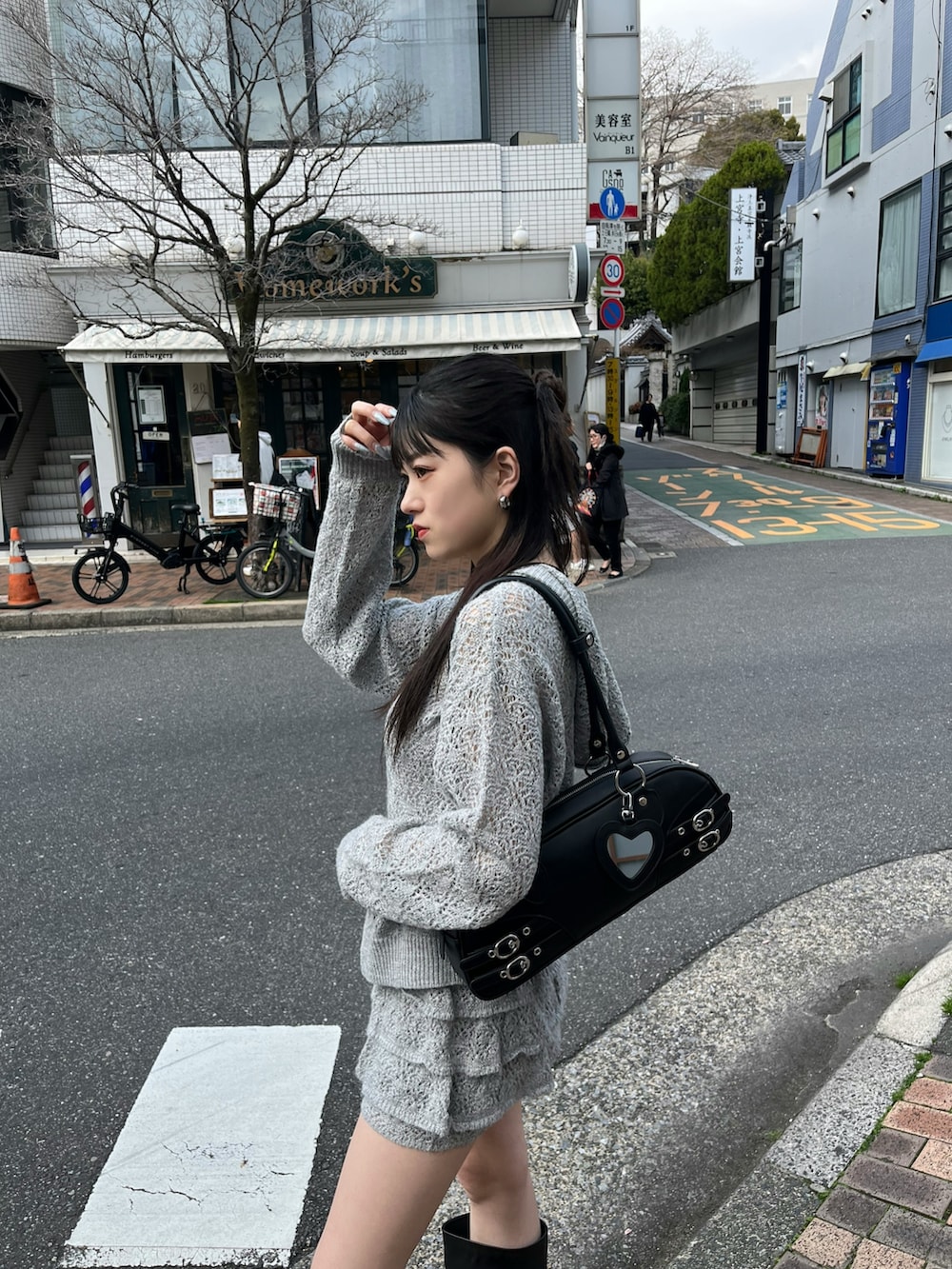 ブラック系のブーツ、ブラック系のハンドバッグ、グレー系のスカートを着用したレディースの春コーディネートの3枚目の写真