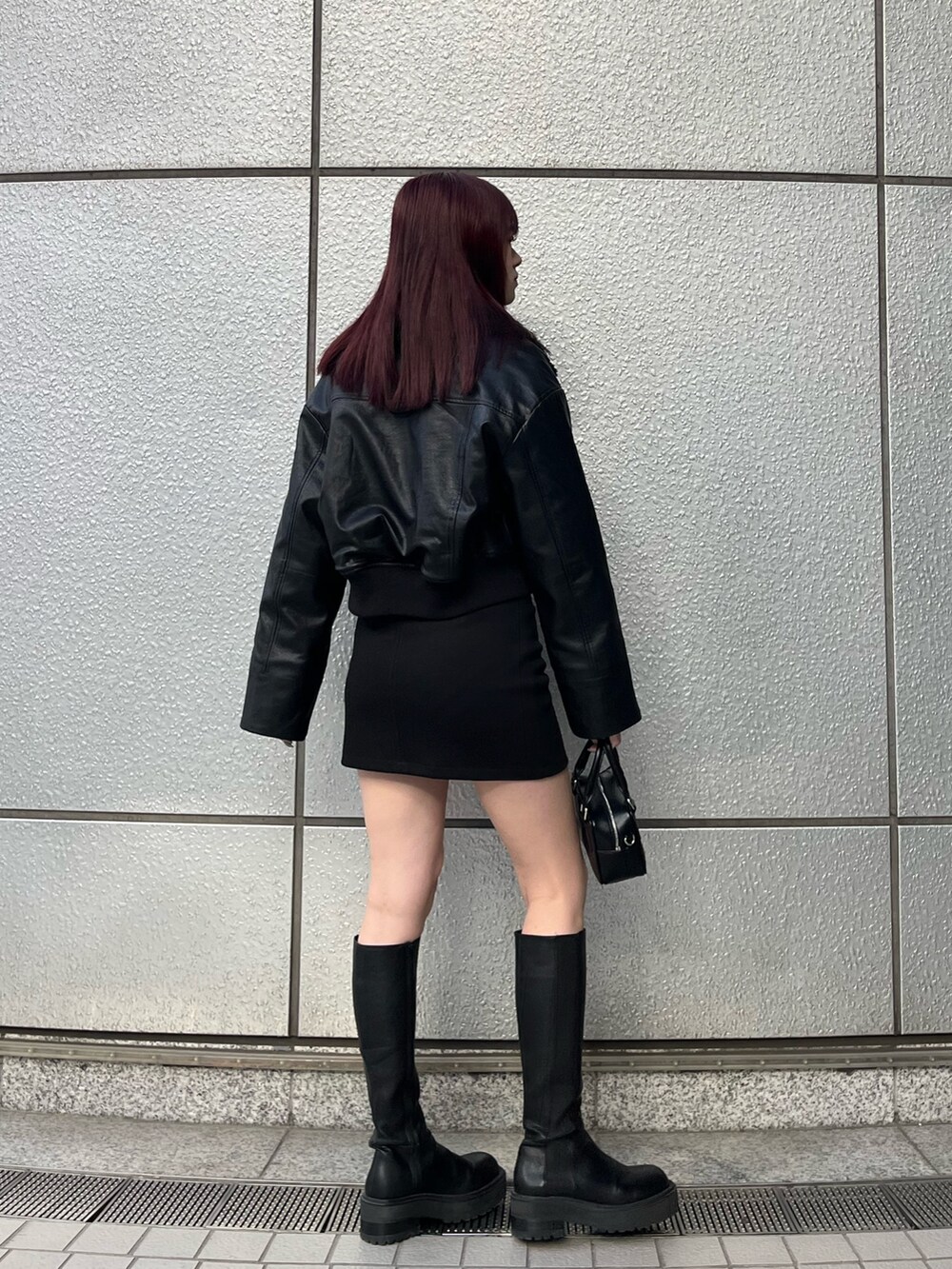 ブラック系のスカート、ブラック系のブルゾン、グレー系のニット/セーターを着用したレディースの冬コーディネートの4枚目の写真