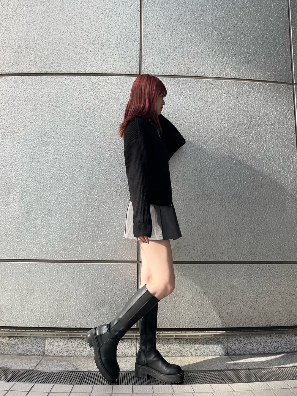 グレー系のスカート、ブラック系のブーツ、ブラック系のニット/セーターを着用したレディースの秋コーディネートの4枚目の写真
